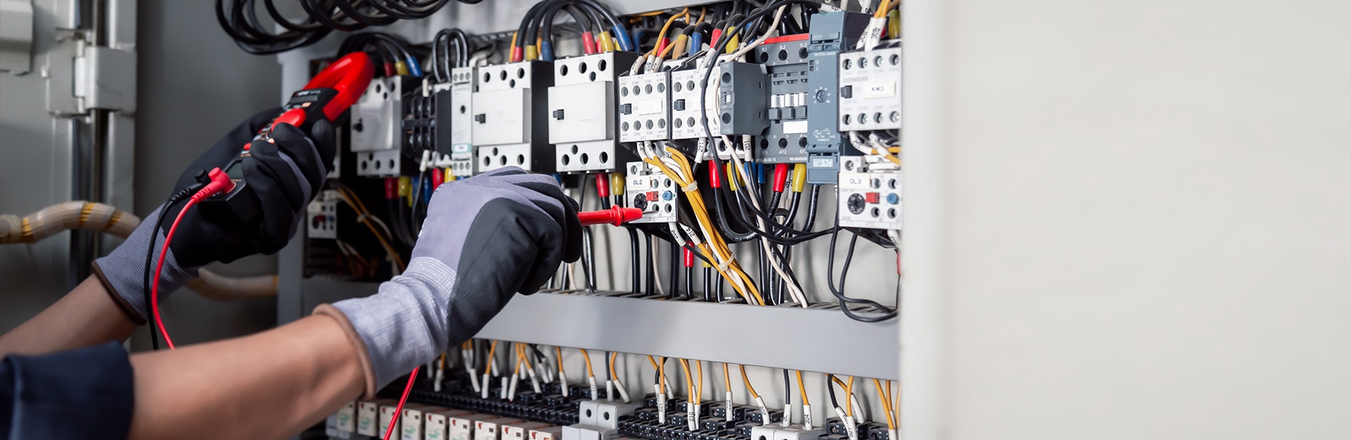 Ein Strieter Mitarbeiter prüft eine elektrotechnische Anlage mithilfe eines Multimeters.